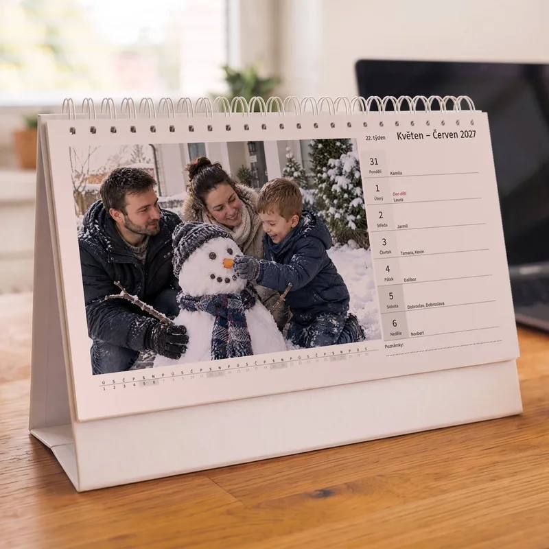 Týdenní stolní fotokalendář na bílém kartonovém stojanu na pracovním stole, vlevo zimní rodinná fotka, vpravo jeden týden