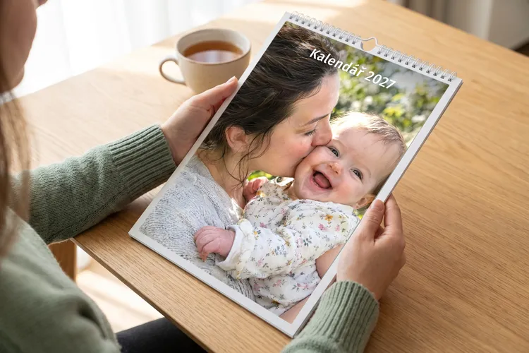 Žena drží nástěnný fotokalendář s fotkou maminky a miminka a nápisem Kalendář 2027